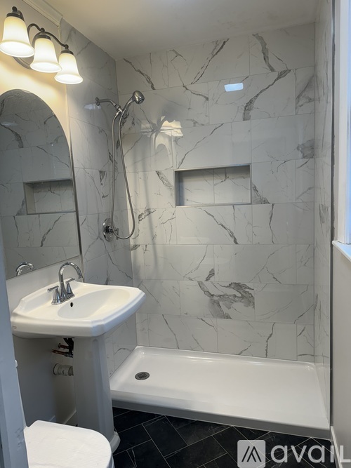 A bathroom with a marble wall and a white toilet.