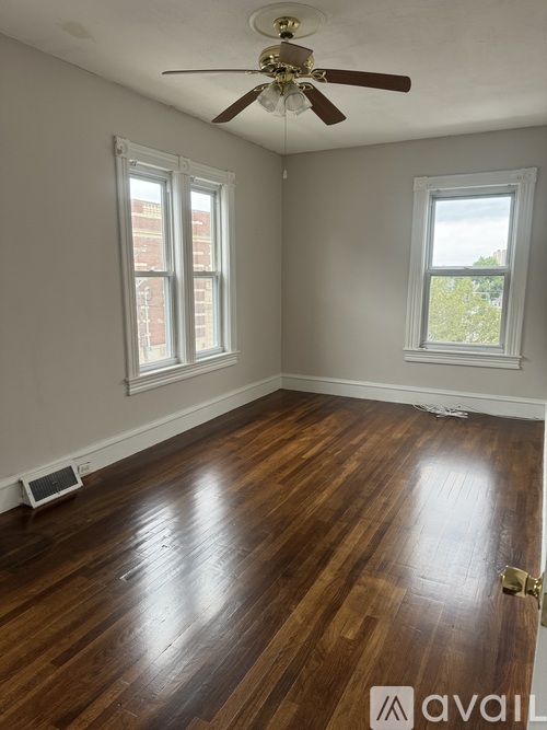 A room with a ceiling fan and two windows.