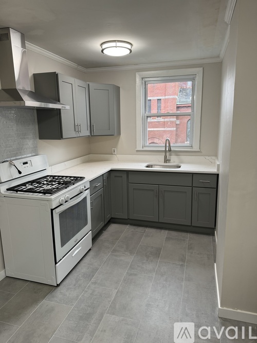 A kitchen with a white stove top oven and a window.