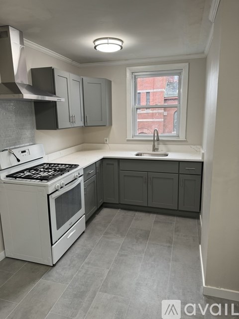 A kitchen with a white stove top oven and a window.