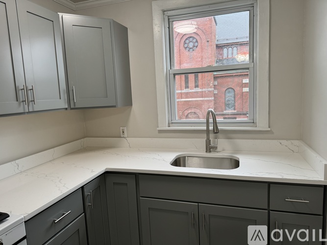 A kitchen with a window overlooking a red brick building.