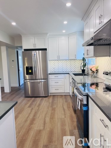 A kitchen with a stainless steel refrigerator and wooden flooring.