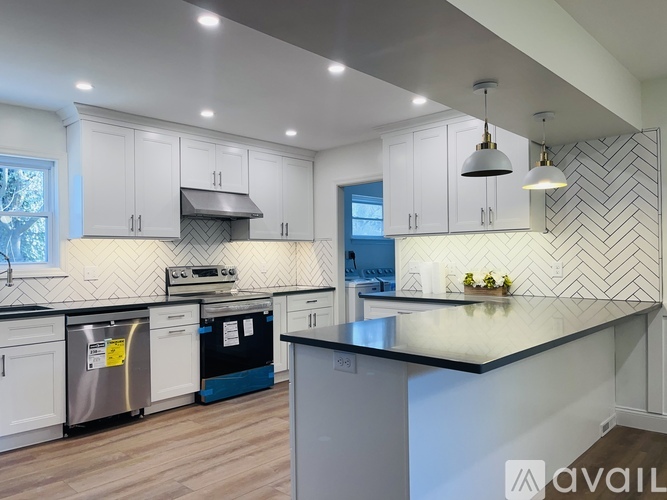 A modern kitchen with a black countertop and white cabinets.