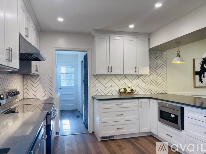 A kitchen with white cabinets and a black and white tiled backsplash.