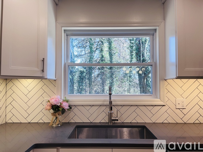 A kitchen with a window overlooking a forest.