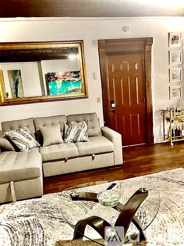 A living room with a couch, a chair, and a rug.