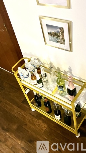 A gold bar cart with a variety of drinks on it.