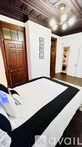 A bedroom with a bed, a door, and pictures on the wall.