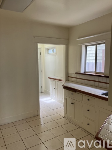 A kitchen with white cabinets and a window.
