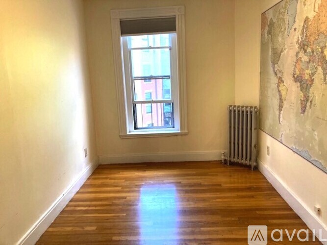 A room with a wooden floor, a window, and a world map on the wall.