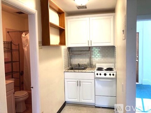 A kitchen with white cabinets and a white stove top oven.