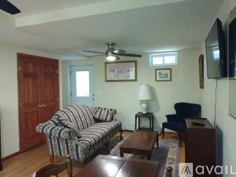 A living room with a striped couch and a ceiling fan.