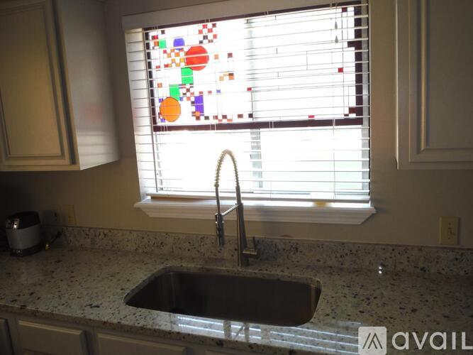 A kitchen with a sink and a window with blinds.