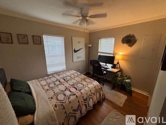 A bedroom with a bed, desk, and ceiling fan.
