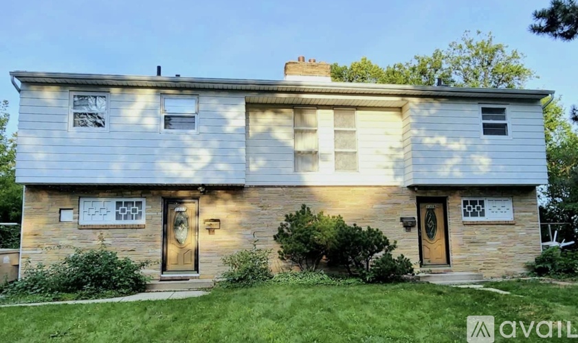 A two-story house with a front yard and a brown door.
