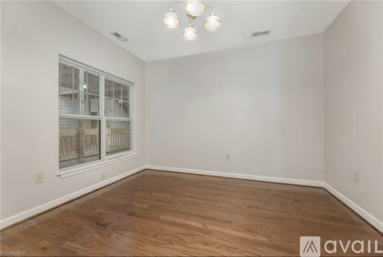 A room with wooden flooring and a window with blinds.