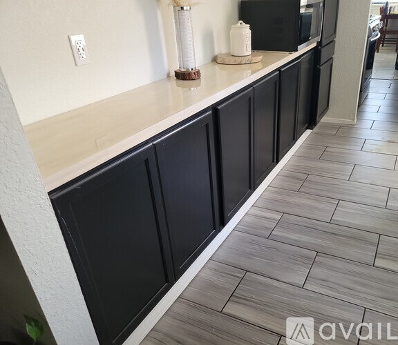 A kitchen with black cabinets and a tiled floor.