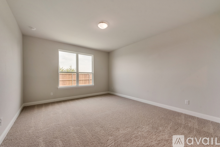 A spacious room with a window and carpeted floor.