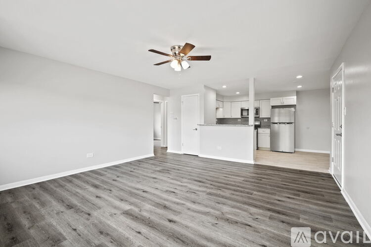 A spacious room with a ceiling fan and wooden flooring.