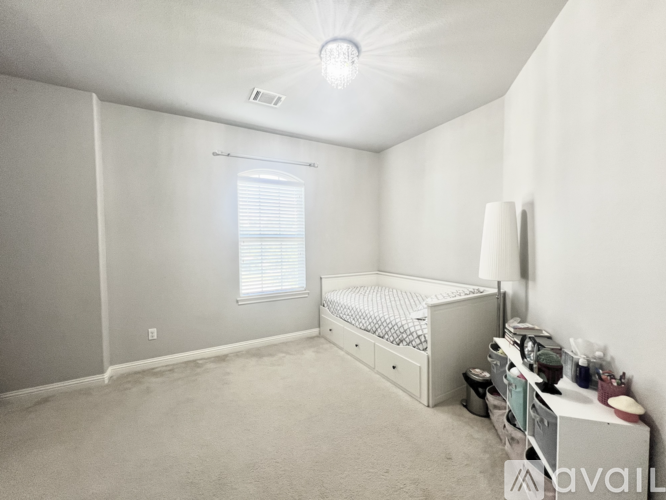 A white bedroom with a bed, nightstand, and window.