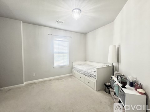 A white bedroom with a bed, nightstand, and window.