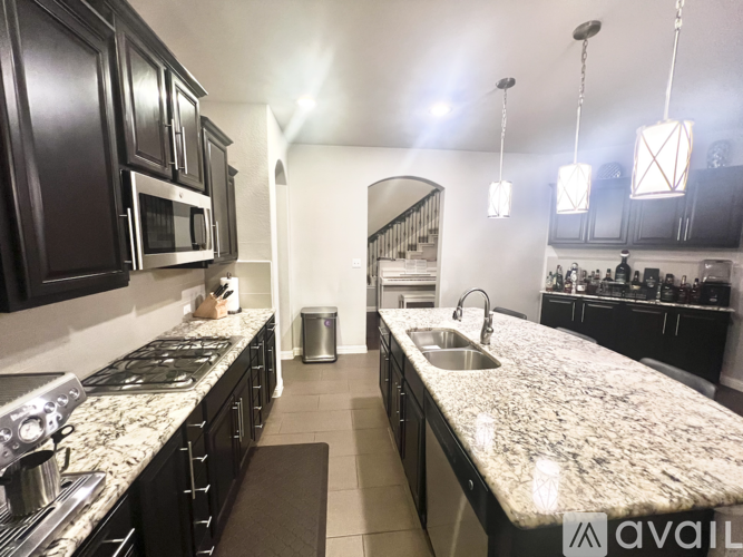 A kitchen with granite countertops and dark cabinets.