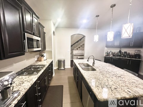 A kitchen with granite countertops and dark cabinets.
