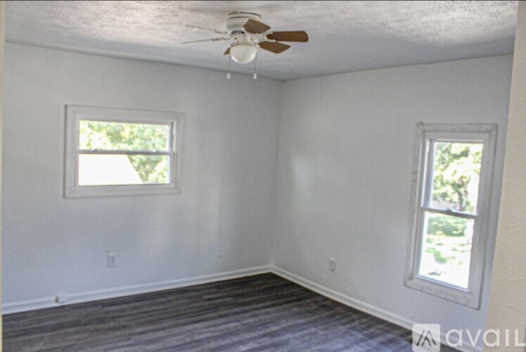 A room with a ceiling fan and two windows.