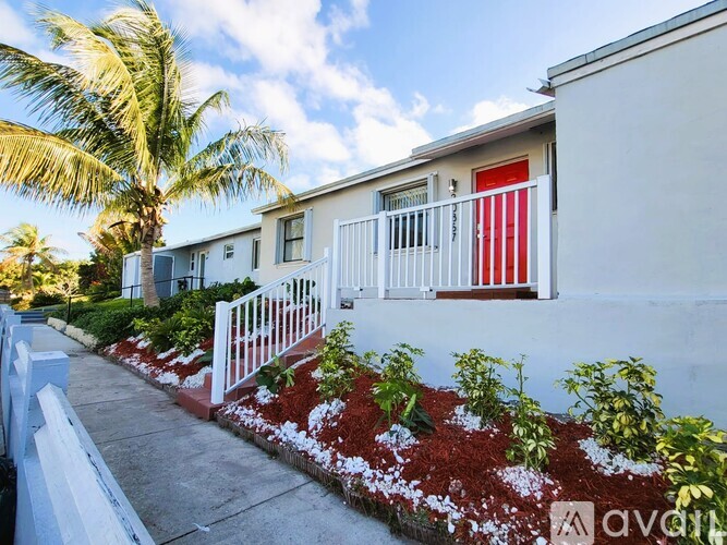 A white house with a red door and a white fence.
