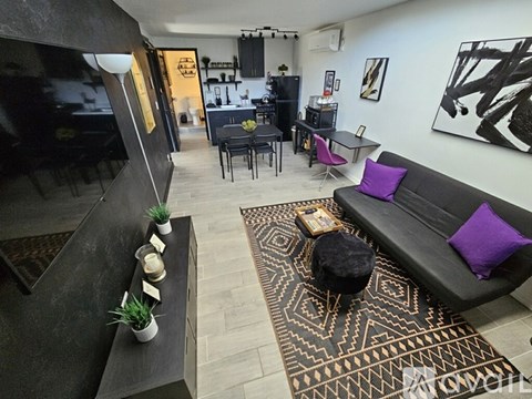 A living room with a black couch and a patterned rug.