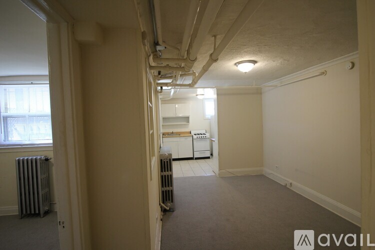 A room with a window, a radiator, and a white fridge in the corner.