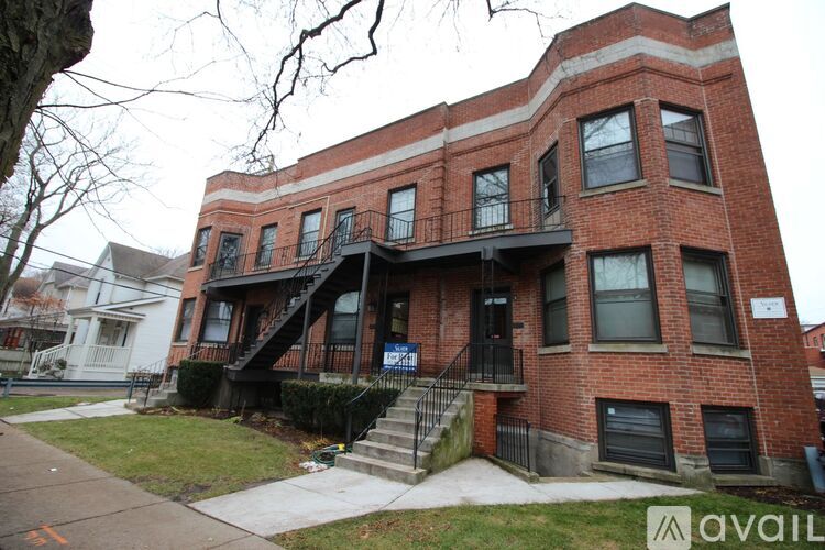 A red brick building with a black railing on the balcony.
