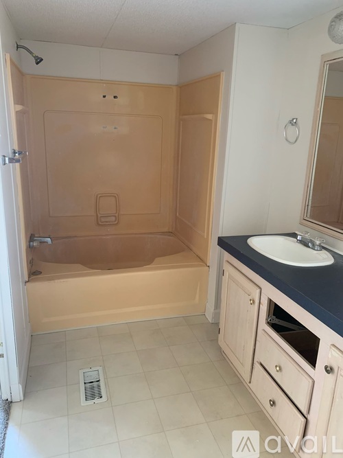 A bathroom with a tub, sink, and mirror.