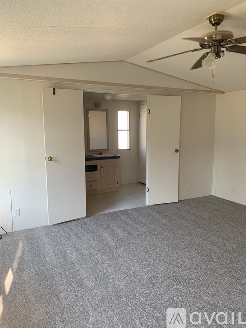 A room with a carpeted floor and a ceiling fan.