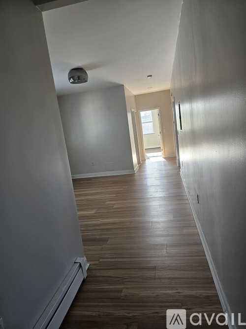 A long hallway with wood floors and white walls.