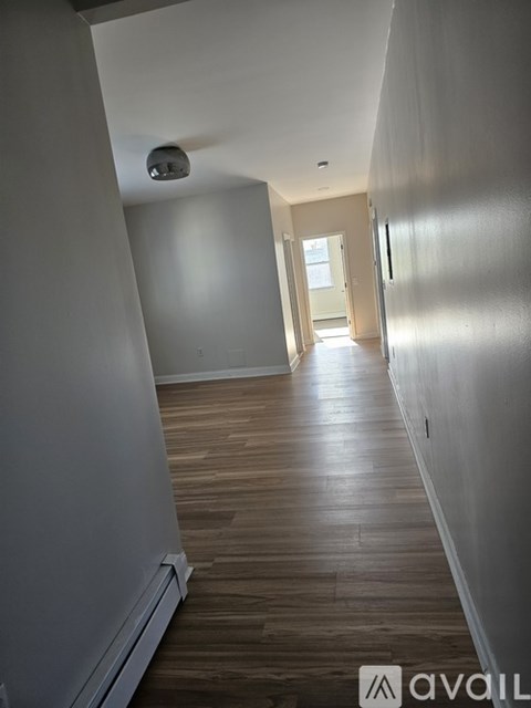 A long hallway with wood floors and white walls.