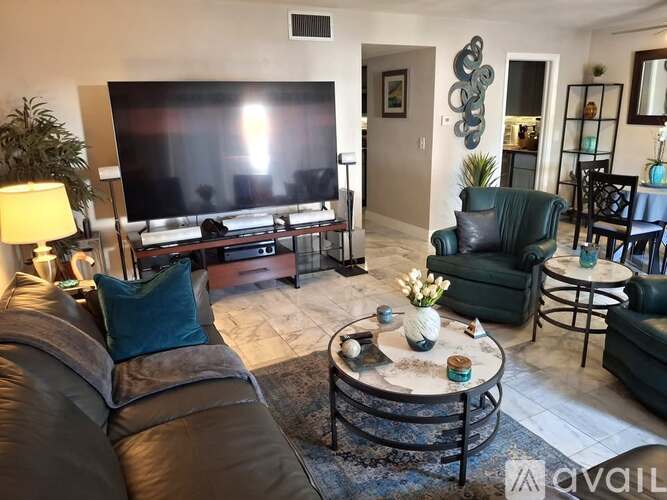A living room with a large screen TV and a brown leather couch.