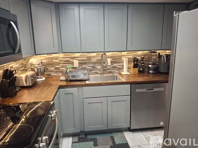 A kitchen with a black stove top oven and a sink with a silver faucet.
