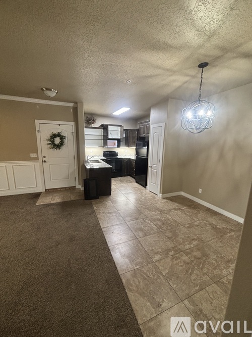 A hallway with a light hanging from the ceiling and a door with a wreath on it.