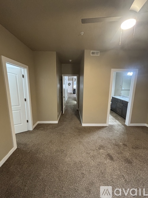 A spacious room with a carpeted floor and a ceiling fan.