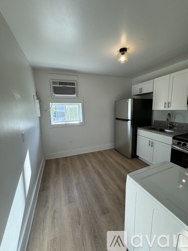 A kitchen with white cabinets and a black fridge.