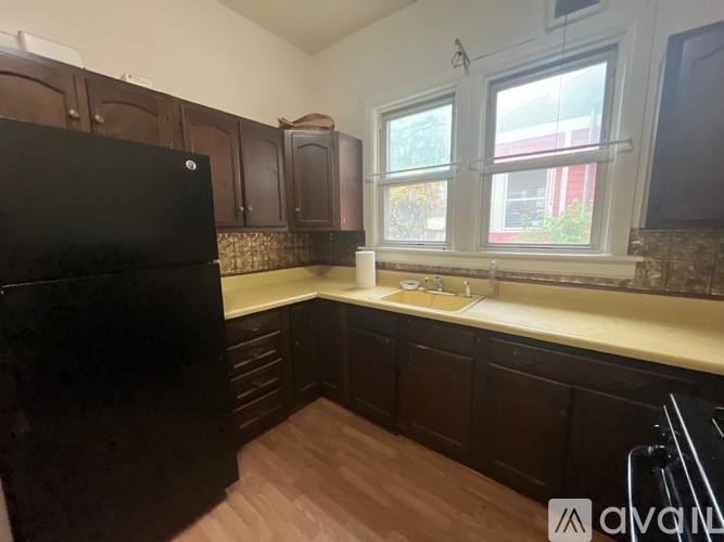 A kitchen with a black refrigerator and wooden cabinets.