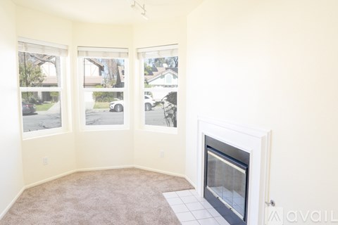 A living room with a fireplace and a carpet on the floor.