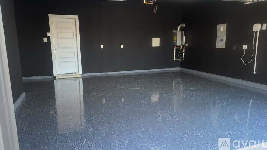 A room with a white door and a black wall with a wet floor.