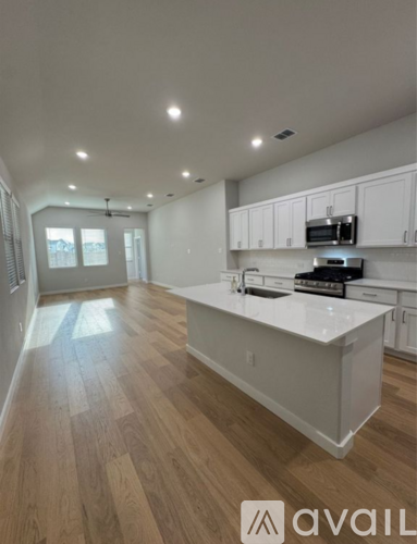 A kitchen with white cabinets and a wooden floor.