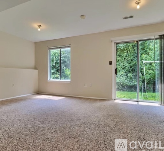A spacious room with a large window and sliding glass doors leading to a garden.
