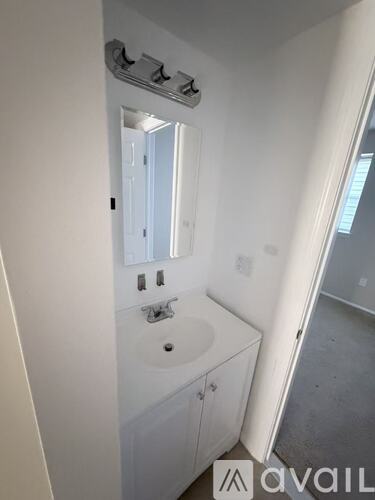 A bathroom with a sink, mirror, and cabinet.