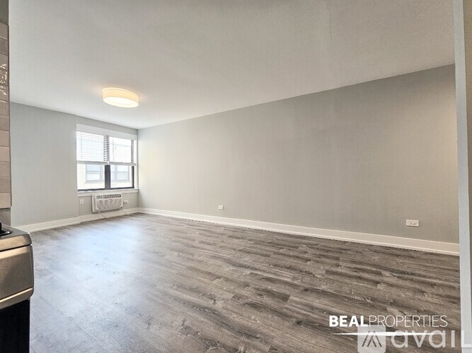 A spacious room with a window and a wooden floor.