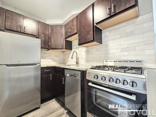 A modern kitchen with a stainless steel refrigerator and a stainless steel gas stove.