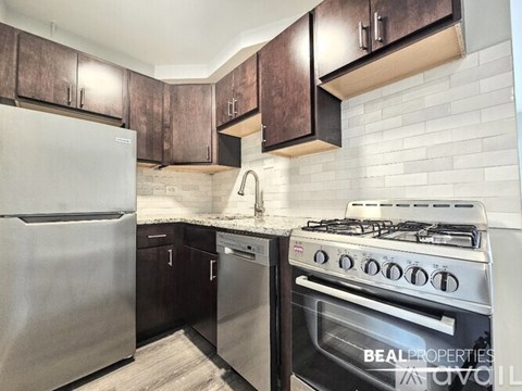 A modern kitchen with a stainless steel refrigerator and a stainless steel gas stove.